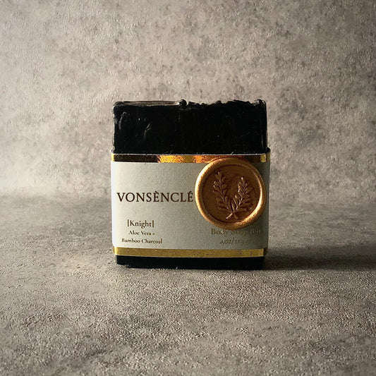 A black-colored soap bar on a gray background.