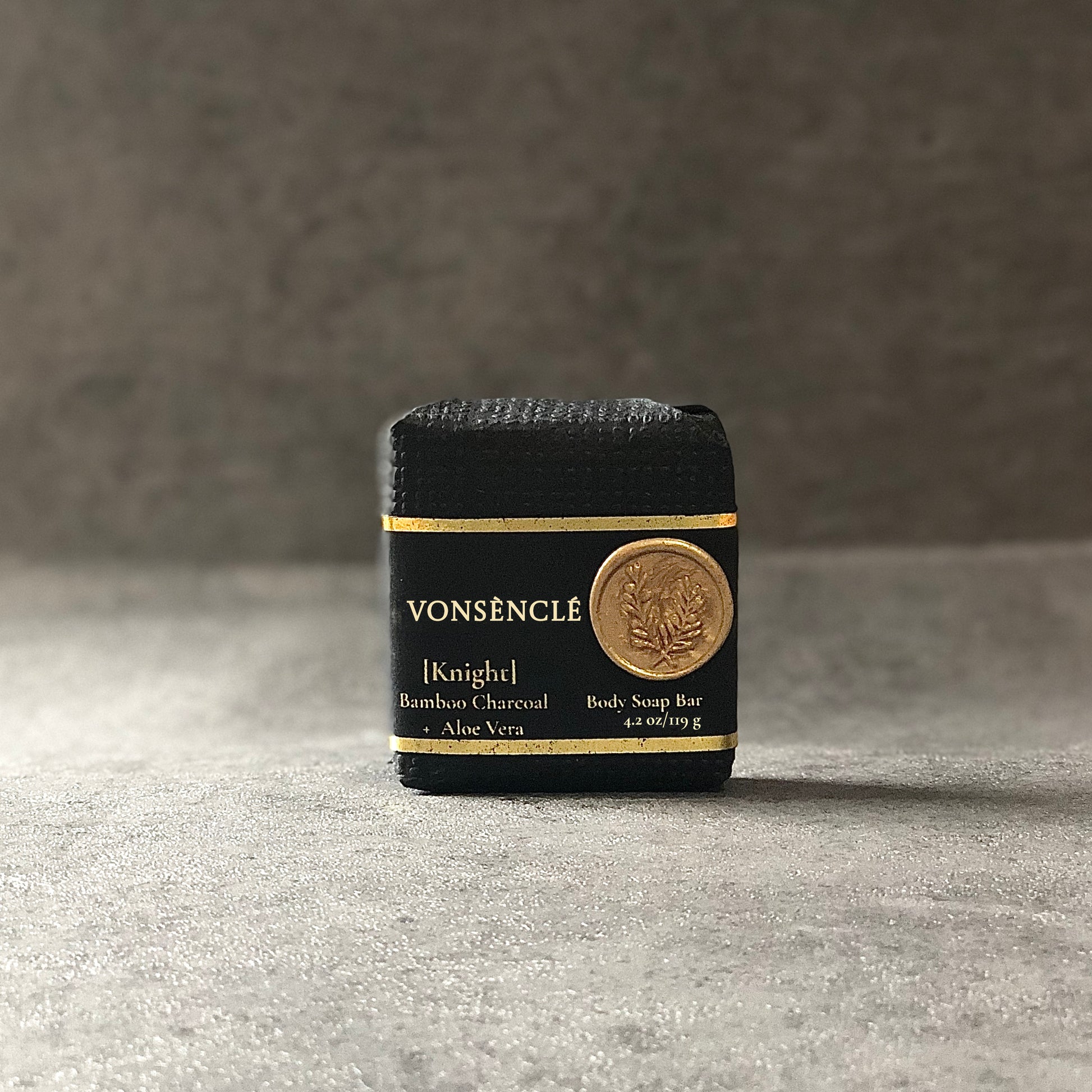 Vonsènclé body soap bar with black packaging on a gray surface.
