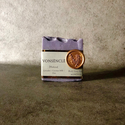 Light purple-colored square soap bar with a grey foiled label on a grey background