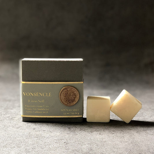A gray-colored label wrapped around a rigid box with soy wax melts being displayed from the brand Vonsènclé.