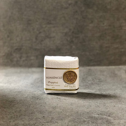 Cold process soap wrapped in a white textured paper that contains a gold-colored wax stamp